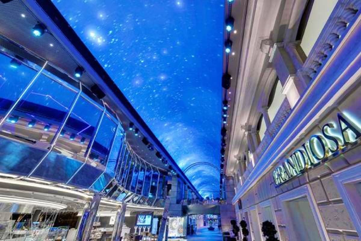 MSC Grandiosa Mediterranean Cruise Modern indoor promenade with blue LED ceiling lighting and glass railings on MSC Grandiosa cruise ship