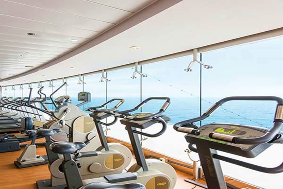 Modern gym with exercise bikes and equipment overlooking the ocean on MSC Grandiosa cruise ship