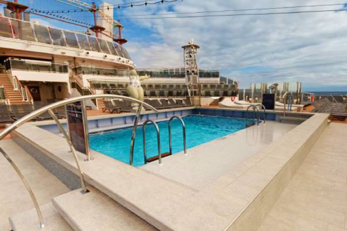 Outdoor swimming pool deck on MSC Grandiosa cruise ship with blue water, white railings, and ship superstructure visible in b