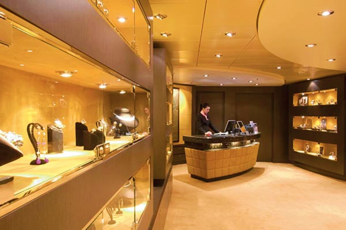 Luxury jewelry store interior on MSC Musica cruise ship with illuminated display cases and sales associate at counter