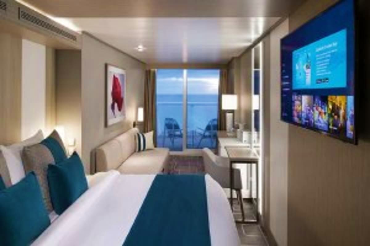 Celebrity Xcel Mediterranean Escape Modern cruise ship stateroom with ocean view balcony, queen bed with teal accents, flat-screen TV, and contemporary furnishin