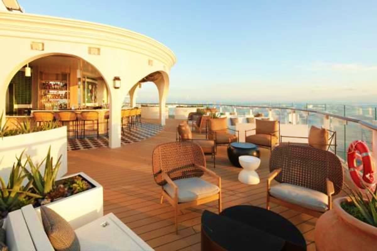 Elegant rooftop deck on Celebrity Xcel cruise ship with lounge seating, bar area, and panoramic ocean views