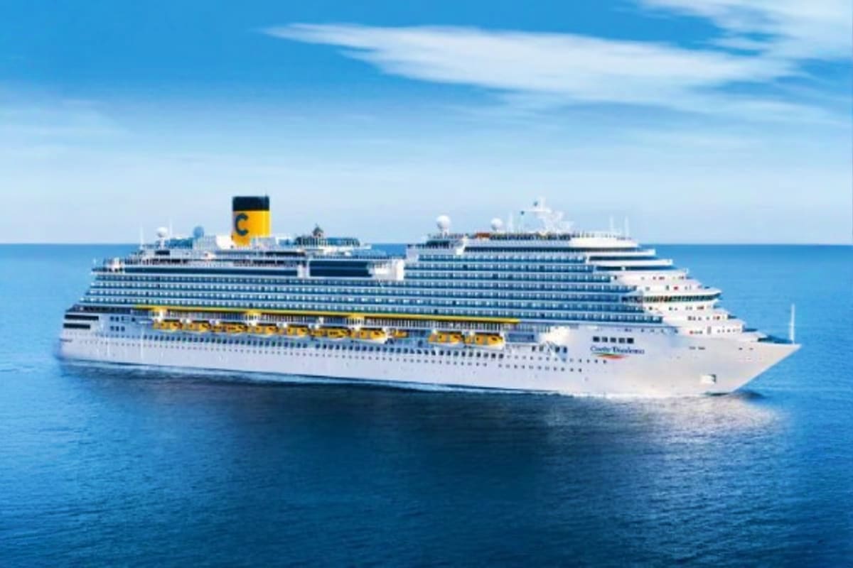 Large white and blue cruise ship with yellow funnel sailing on clear blue ocean under sunny sky