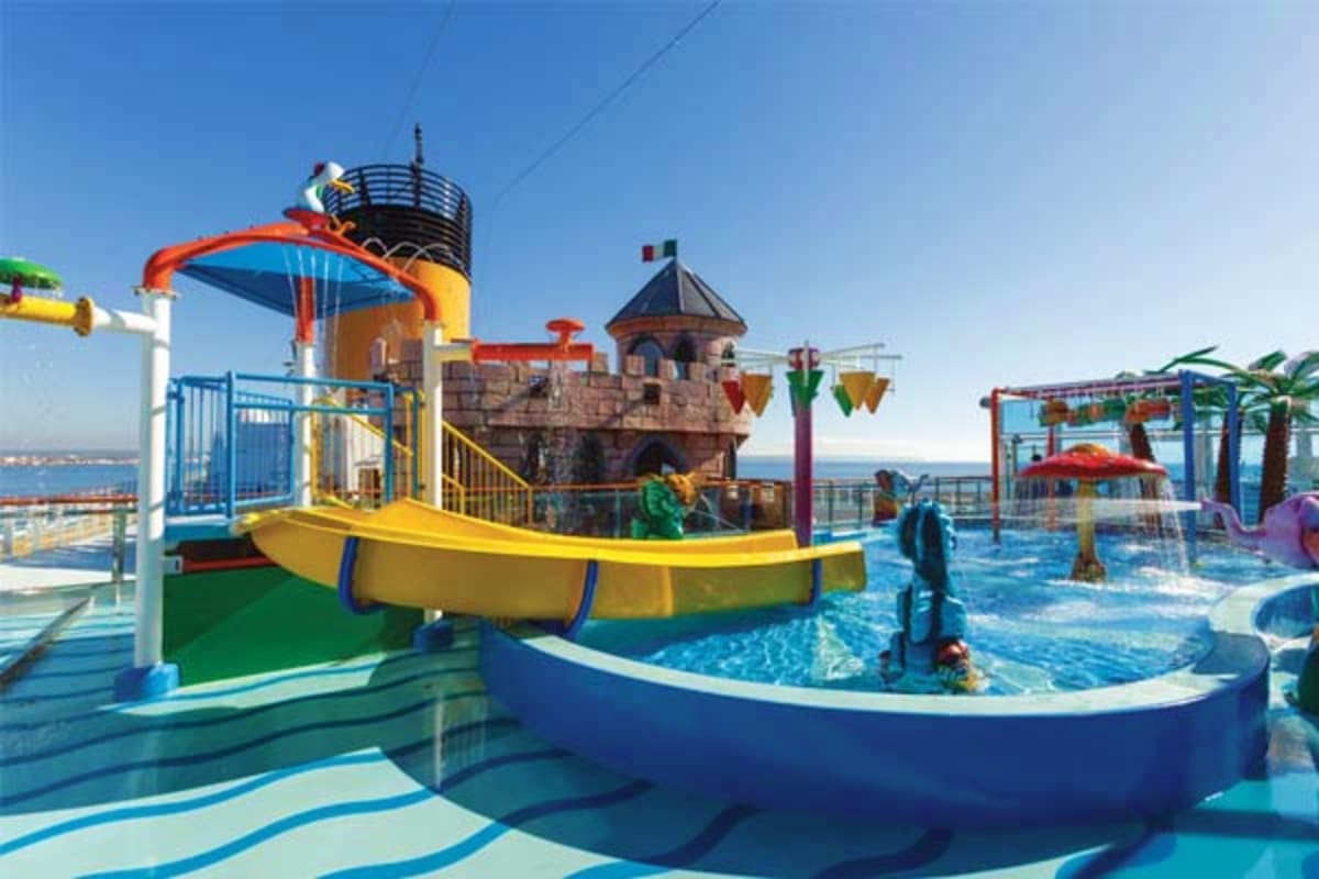 Costa Diadema waterpark with colorful slide, castle tower structure, and shallow pool area with ocean view in background