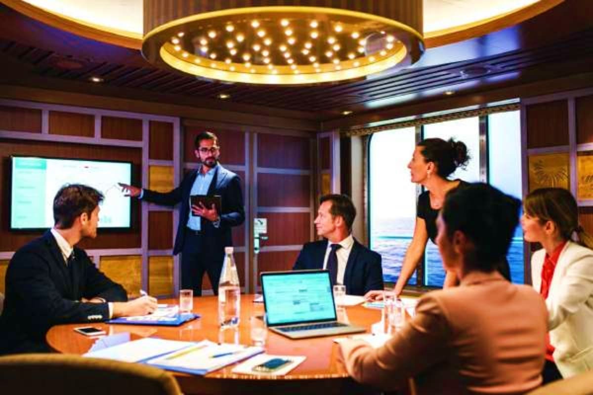 Business professionals in formal attire holding a meeting in a modern conference room with floor-to-ceiling windows overlooki