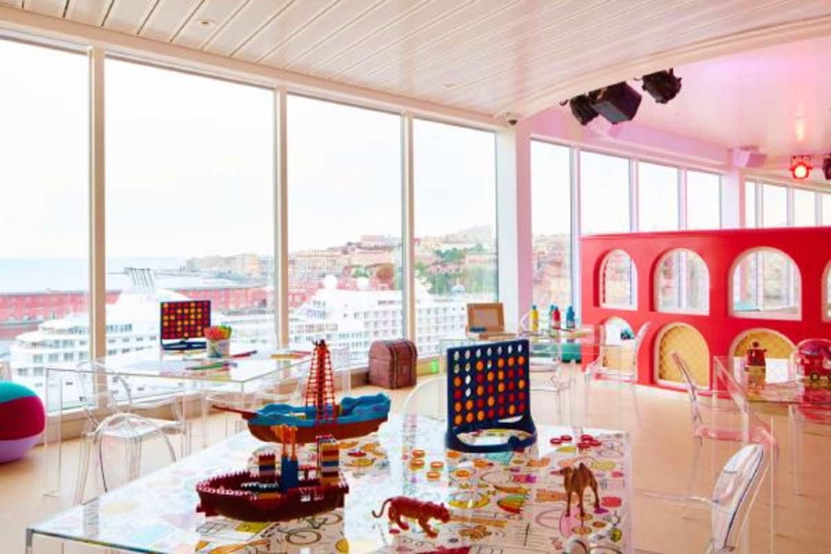 Colorful children's playroom on Costa Diadema cruise ship with toys, games, and panoramic coastal city views through floor-to