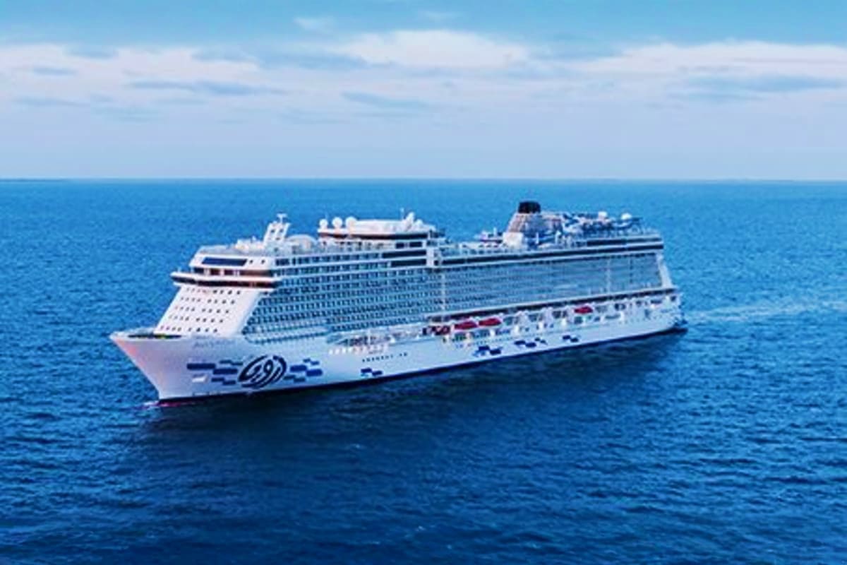 Large white cruise ship sailing on calm blue ocean under clear sky