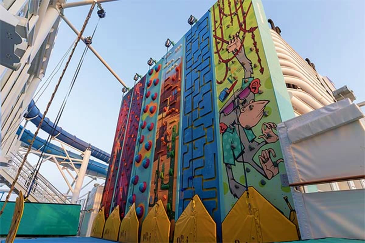 Colorful climbing wall panels on a cruise ship with cartoon character designs and rope climbing features