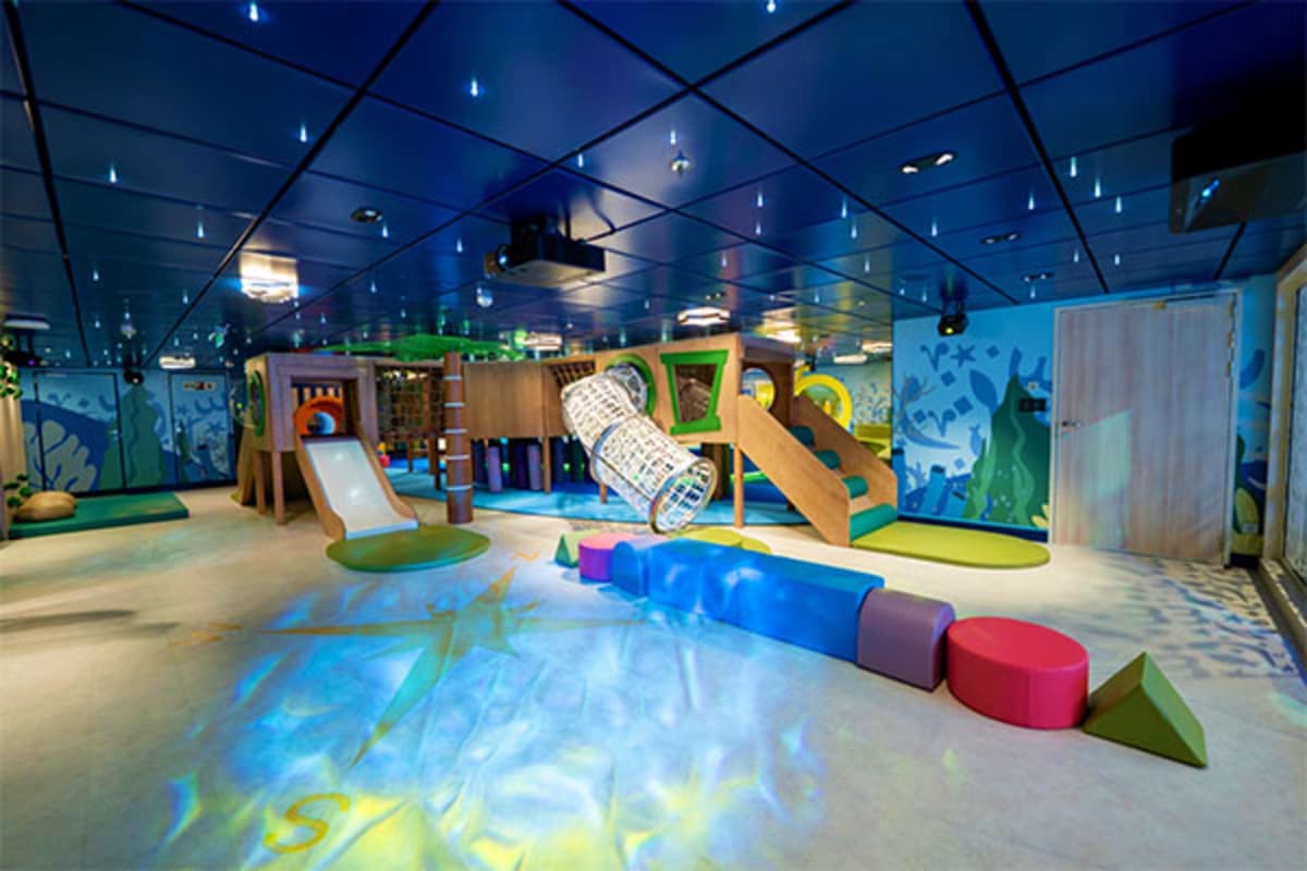 Modern indoor play area with colorful climbing structures, slides, and padded seating in blue-themed children's entertainment