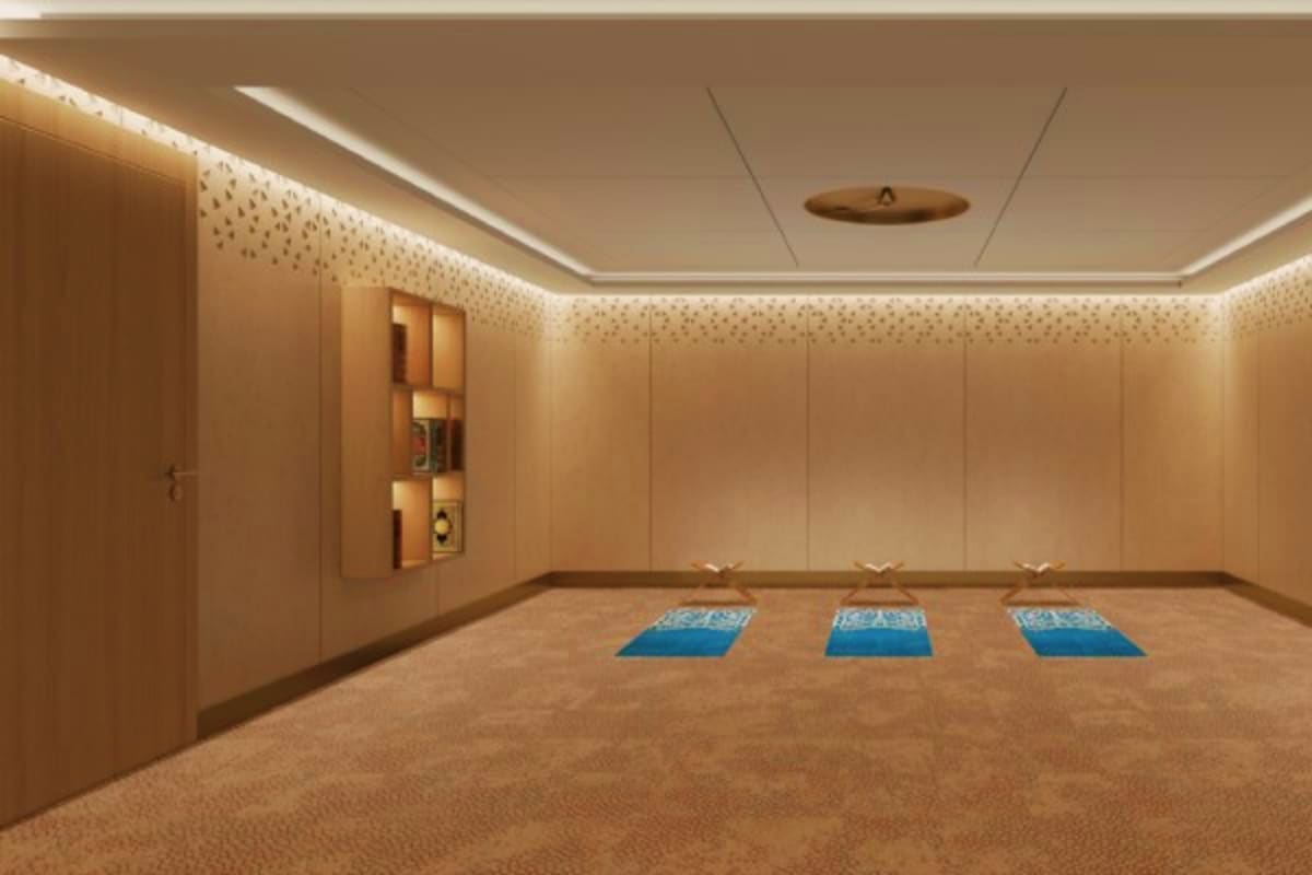 Modern prayer room with three blue prayer mats on beige carpet, wooden wall panels, and ambient ceiling lighting