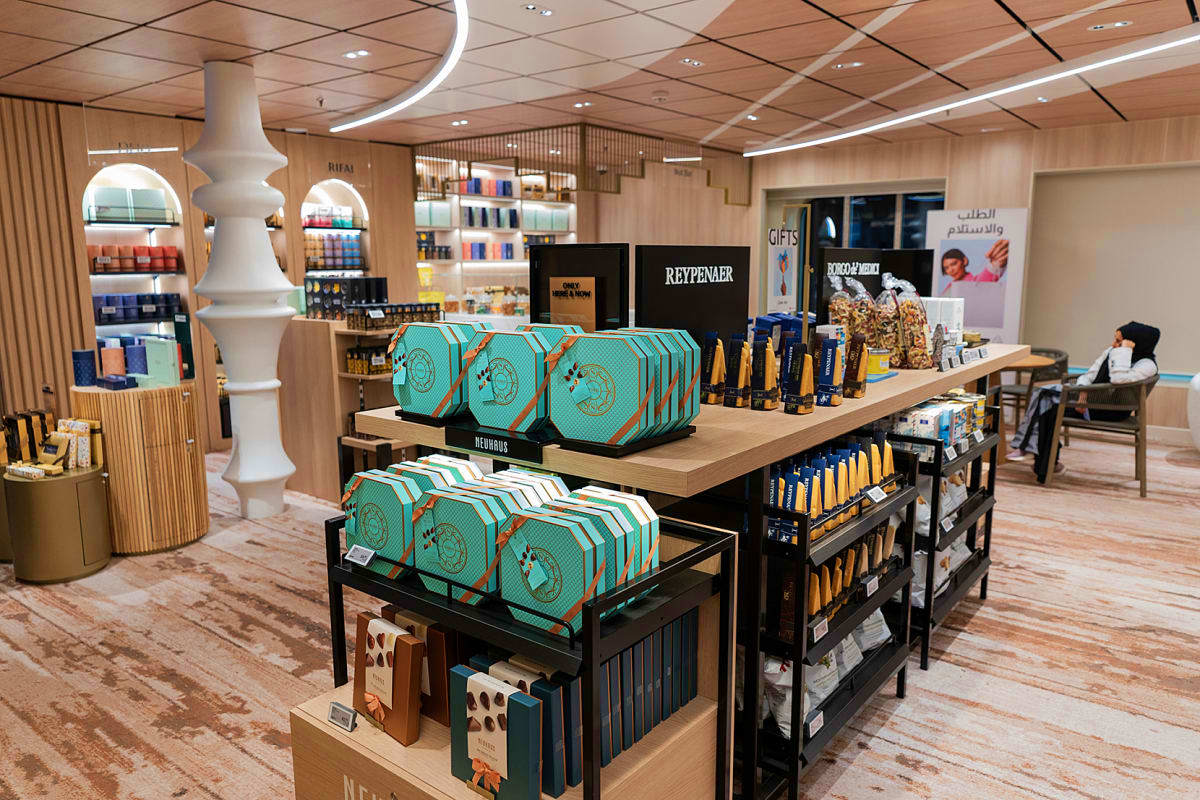 Modern retail shop interior displaying turquoise Aroya branded gift boxes and Reypenaer products on wooden display tables wit
