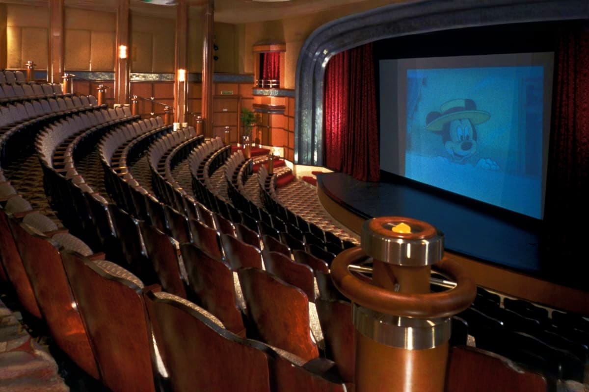 Luxurious home theater room aboard Disney Fantasy cruise ship with rows of leather seats facing large screen displaying Disne