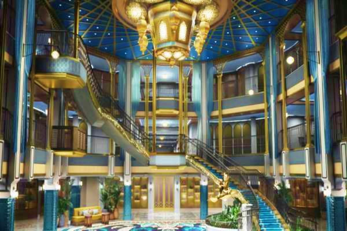 Luxurious multi-level atrium interior of Disney Treasure cruise ship with gold accents, blue ceiling, grand staircase, and or