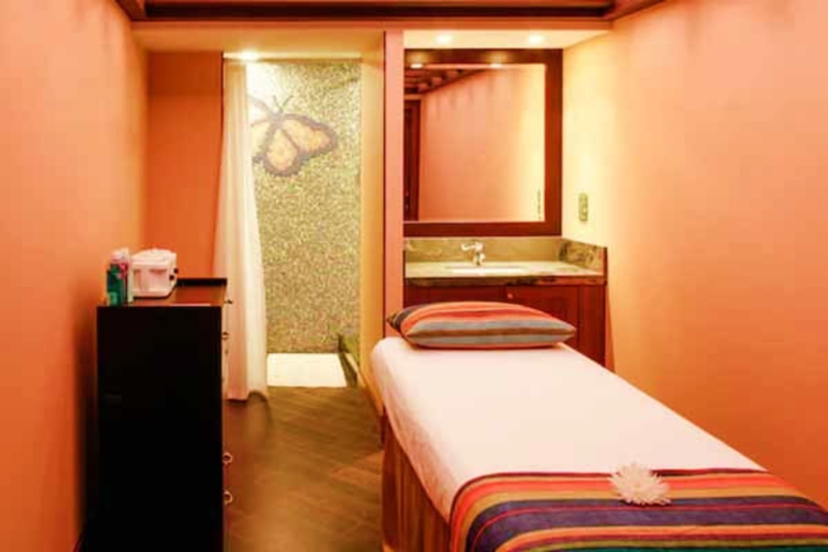 Compact cruise ship cabin with orange walls, single bed, ensuite bathroom, and integrated furniture on the Disney Dream