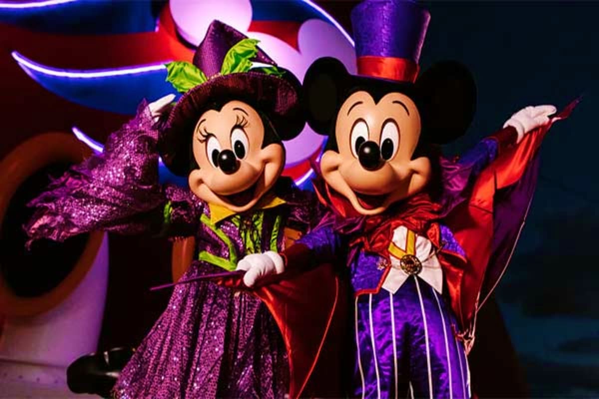 Minnie and Mickey Mouse in sparkly purple and red costumes performing on stage with colorful neon lights and decorative props
