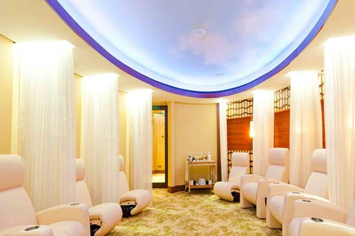 Modern spa treatment room with individual white pods and purple curved ceiling with LED lighting on Disney Dream ship