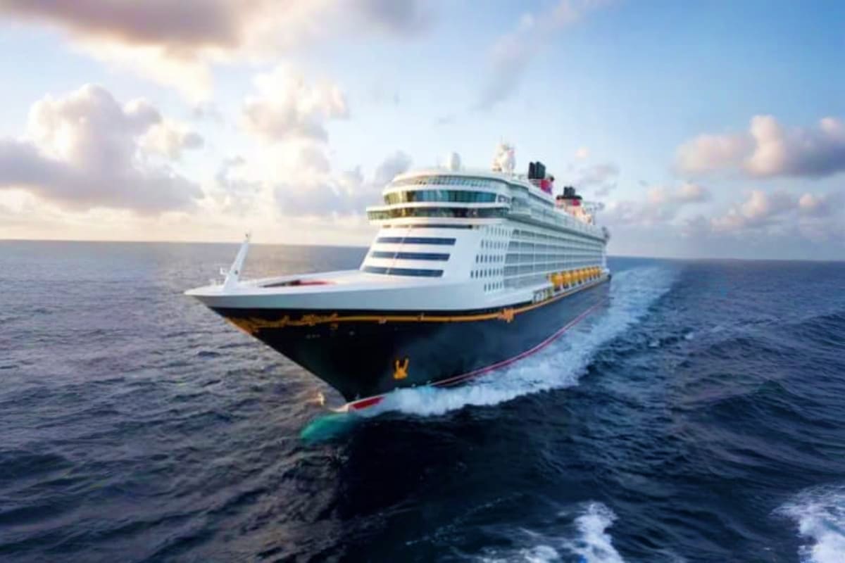 Large white and blue Disney cruise ship on open ocean with cloudy sky and calm waters