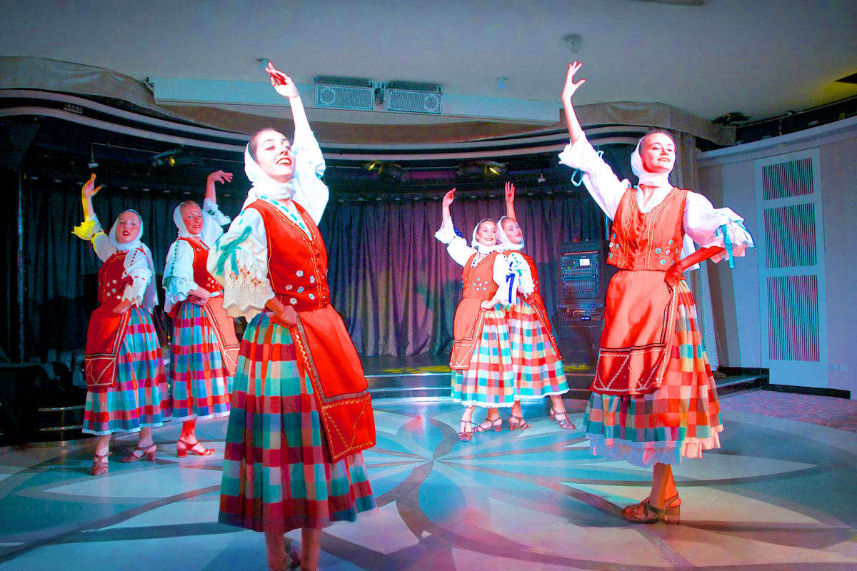 Performers in traditional Icelandic red and turquoise checkered costumes dancing on stage during cultural entertainment show
