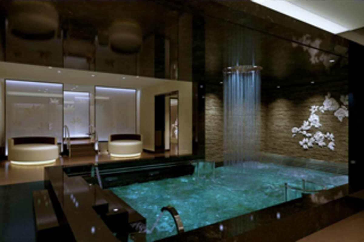 Modern luxury spa interior with illuminated cylindrical seating, rain shower fixture, decorative white orchids, and teal-tile