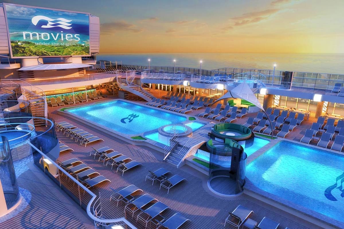 Illuminated swimming pools and loungers on Enchanted Princess cruise ship deck at dusk with movie screen displaying "Movies U