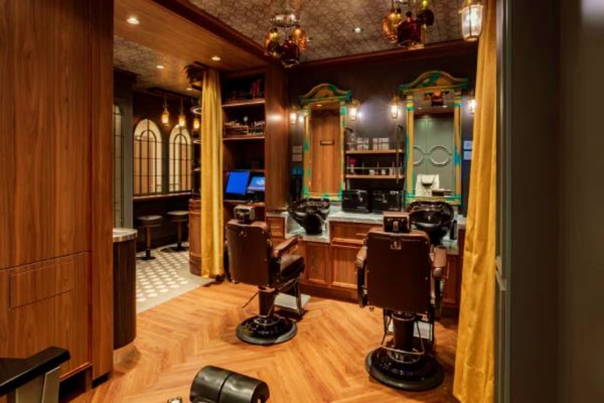 Luxury barbershop interior on Disney Treasure cruise ship with vintage-style barber chairs, wood paneling, gold curtains, and