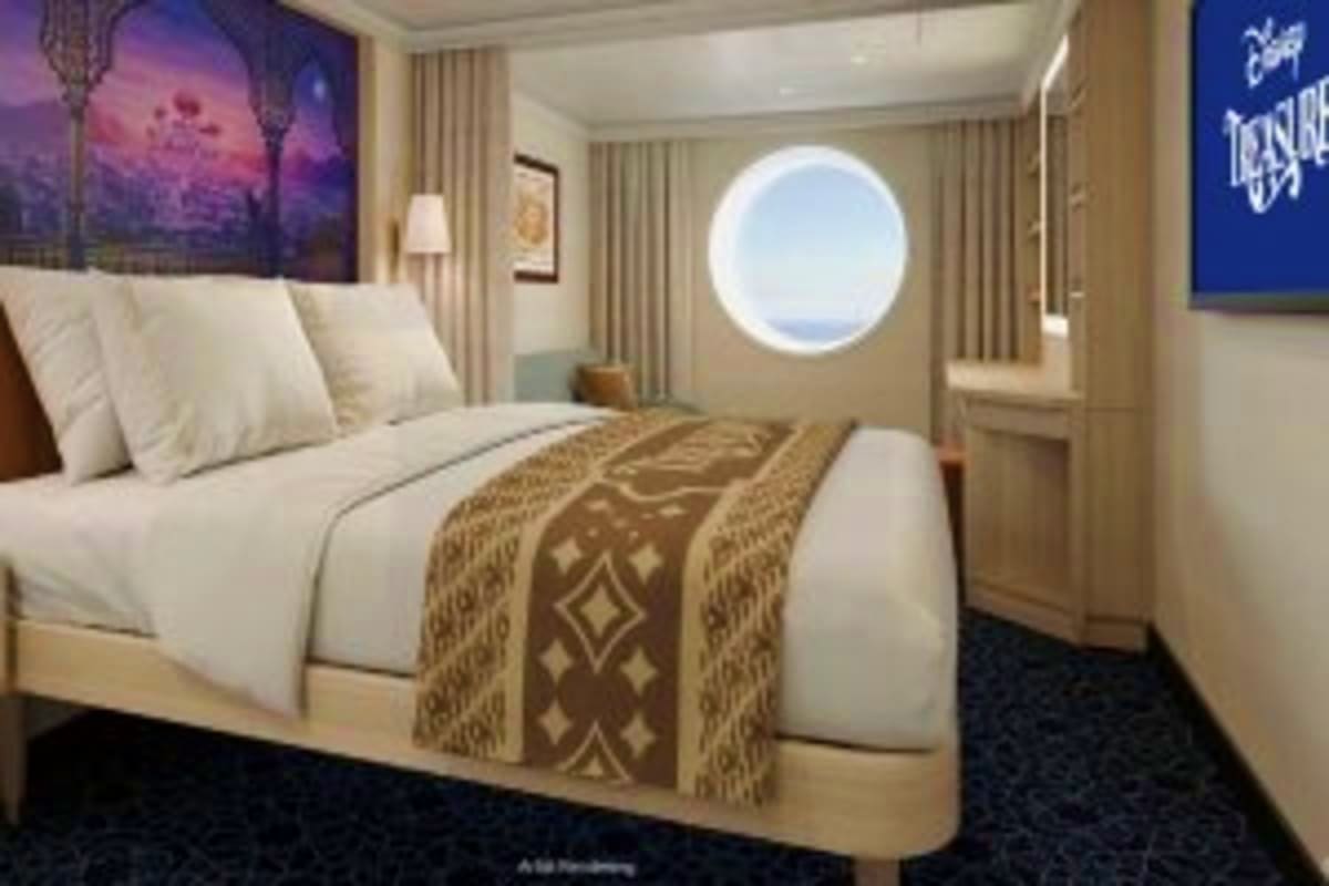Luxury cruise ship stateroom with porthole window, queen bed with decorative throw, beige curtains, and modern furnishings
