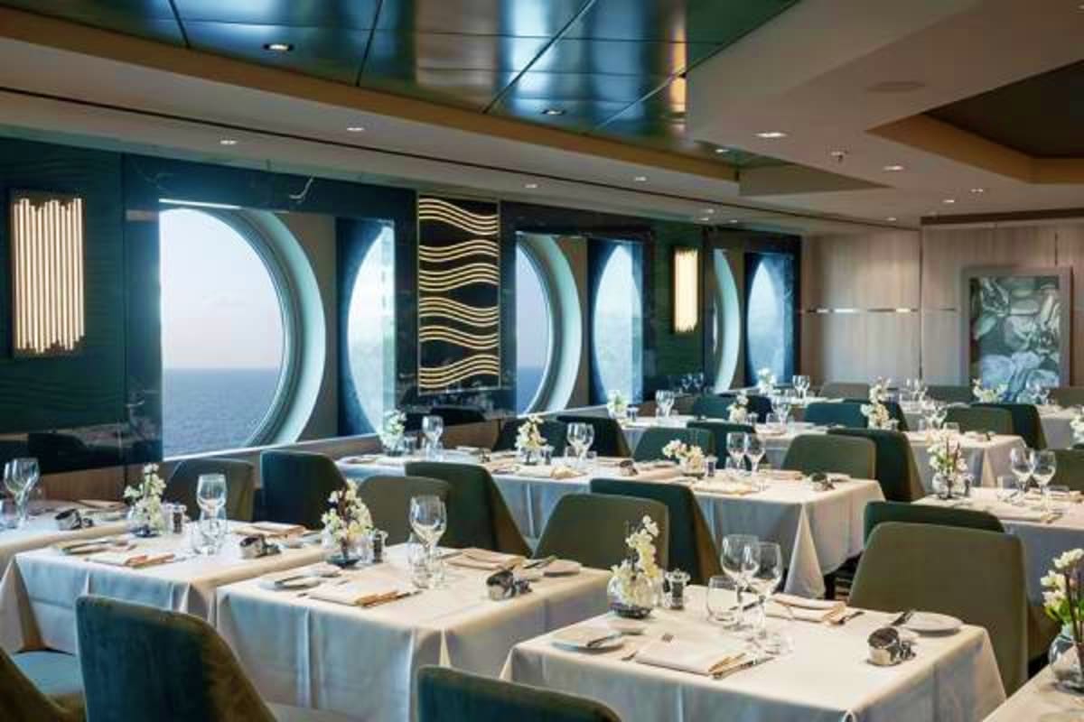 Elegant dining room on MSC Euribia cruise ship with white tablecloths, formal place settings, and panoramic ocean views throu