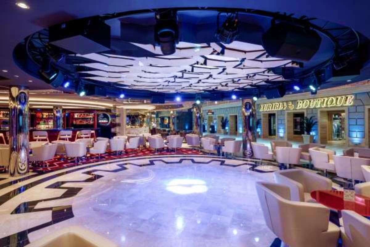 Modern cruise ship nightclub interior with illuminated dance floor, white seating, blue ceiling lights, and "Burlesque Boutiq