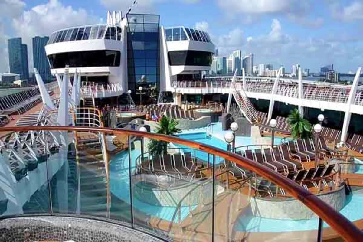 MSC Preziosa cruise ship pool deck with lounge chairs, swimming pools, and city skyline in background