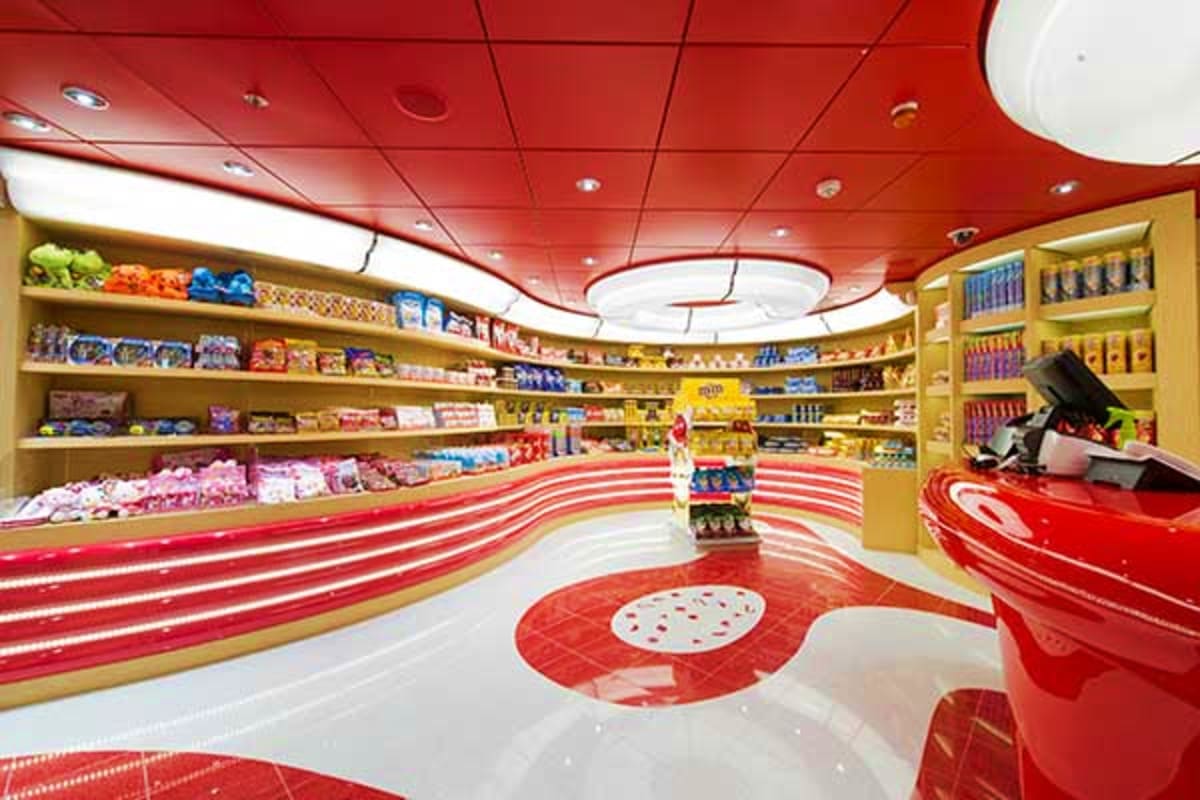 Modern candy shop interior on MSC Preziosa with red and white striped floor, yellow shelving stocked with colorful candies an