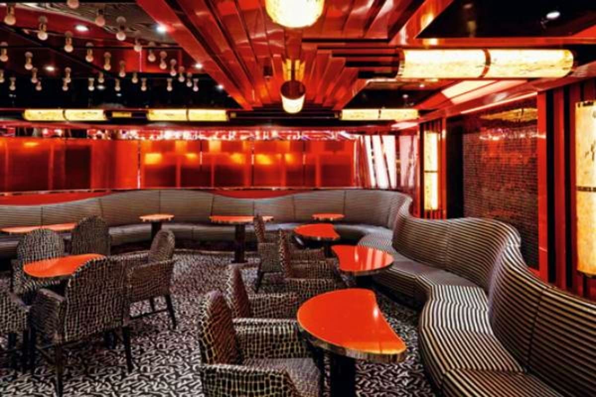 Modern lounge area on Costa Fascinosa cruise ship with red and black contemporary furnishings, curved seating, and illuminate