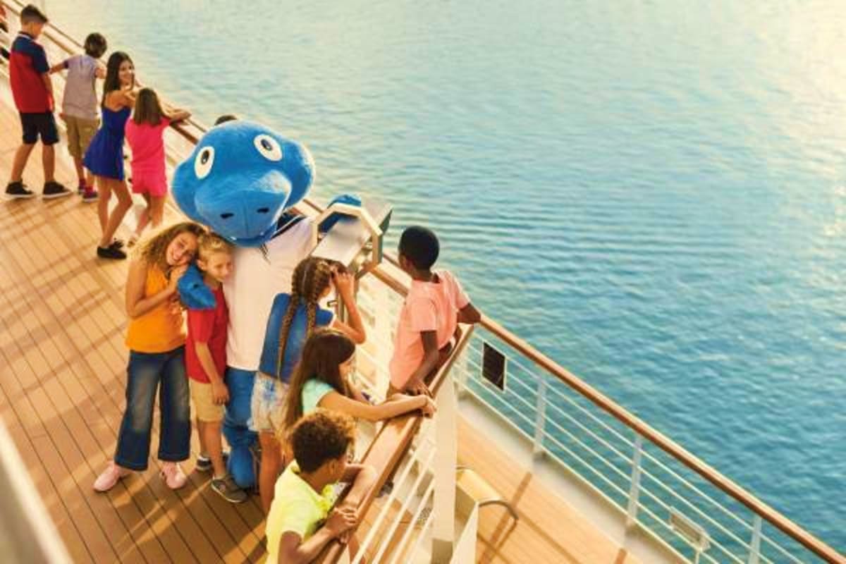 Children and families enjoying deck activities on Costa Fascinosa cruise ship with ocean view and blue mascot character