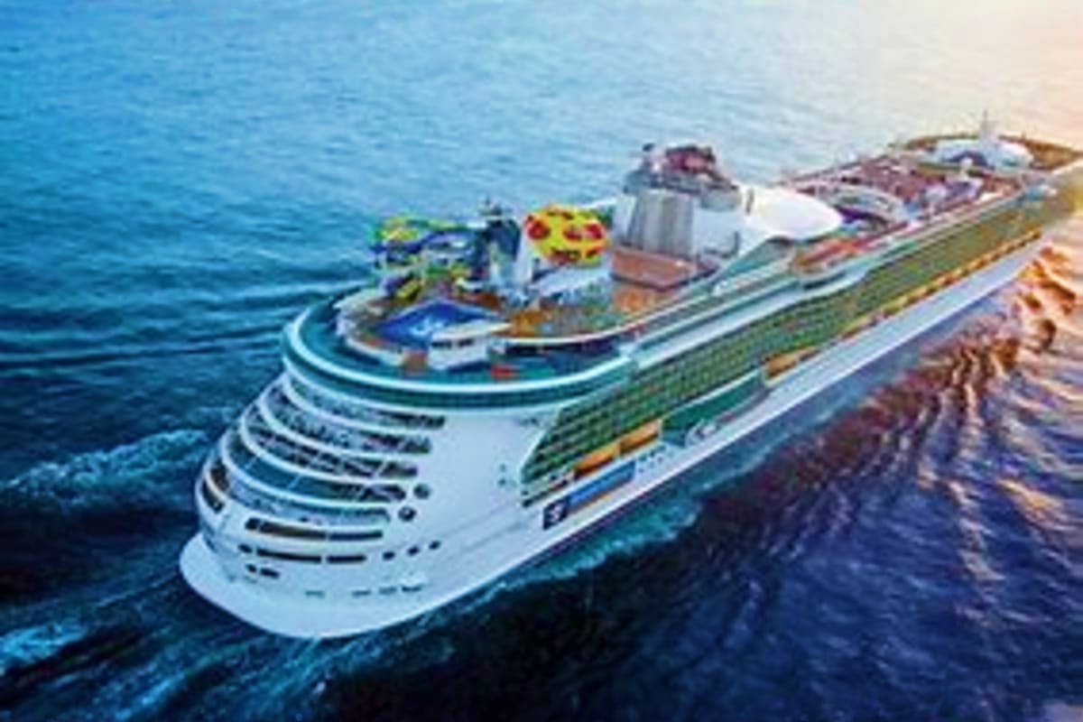 Large cruise ship Independence of the Seas sailing on blue ocean waters near rocky coastal cliffs
