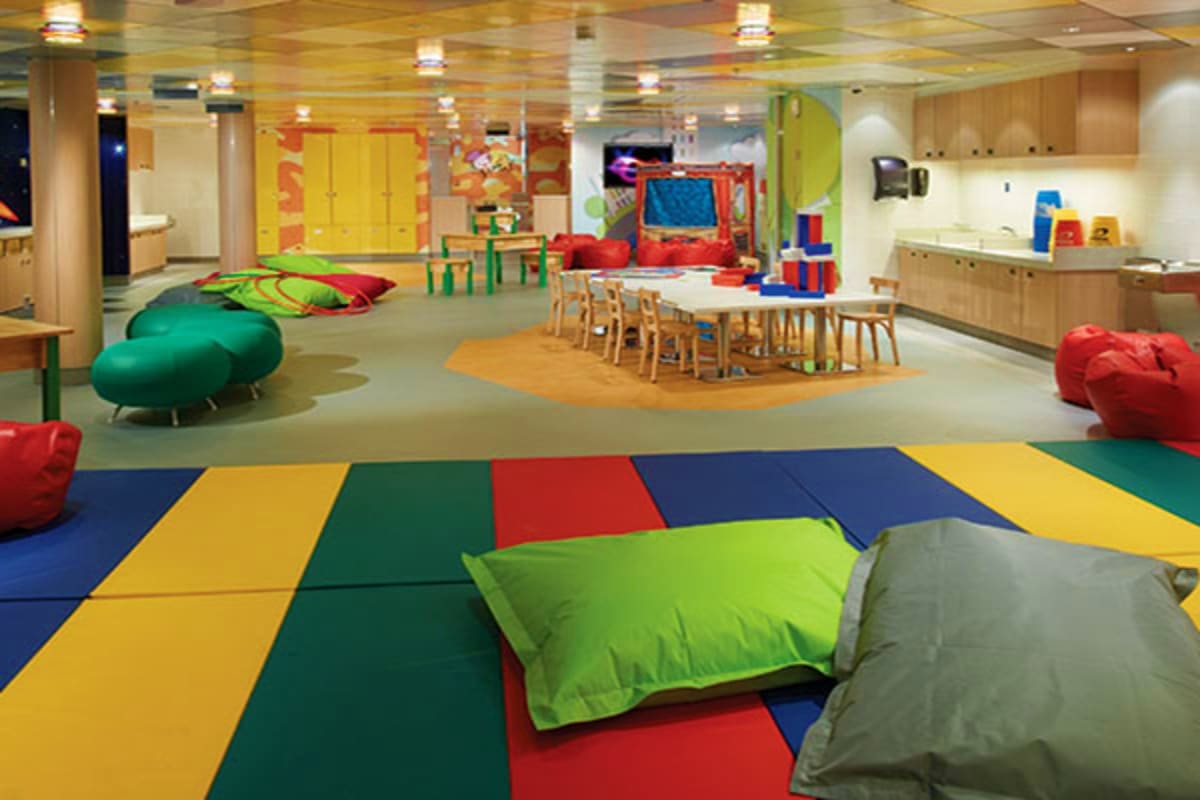 Colorful modern indoor play area with soft mats, bean bags, activity stations, and children's furniture on a cruise ship