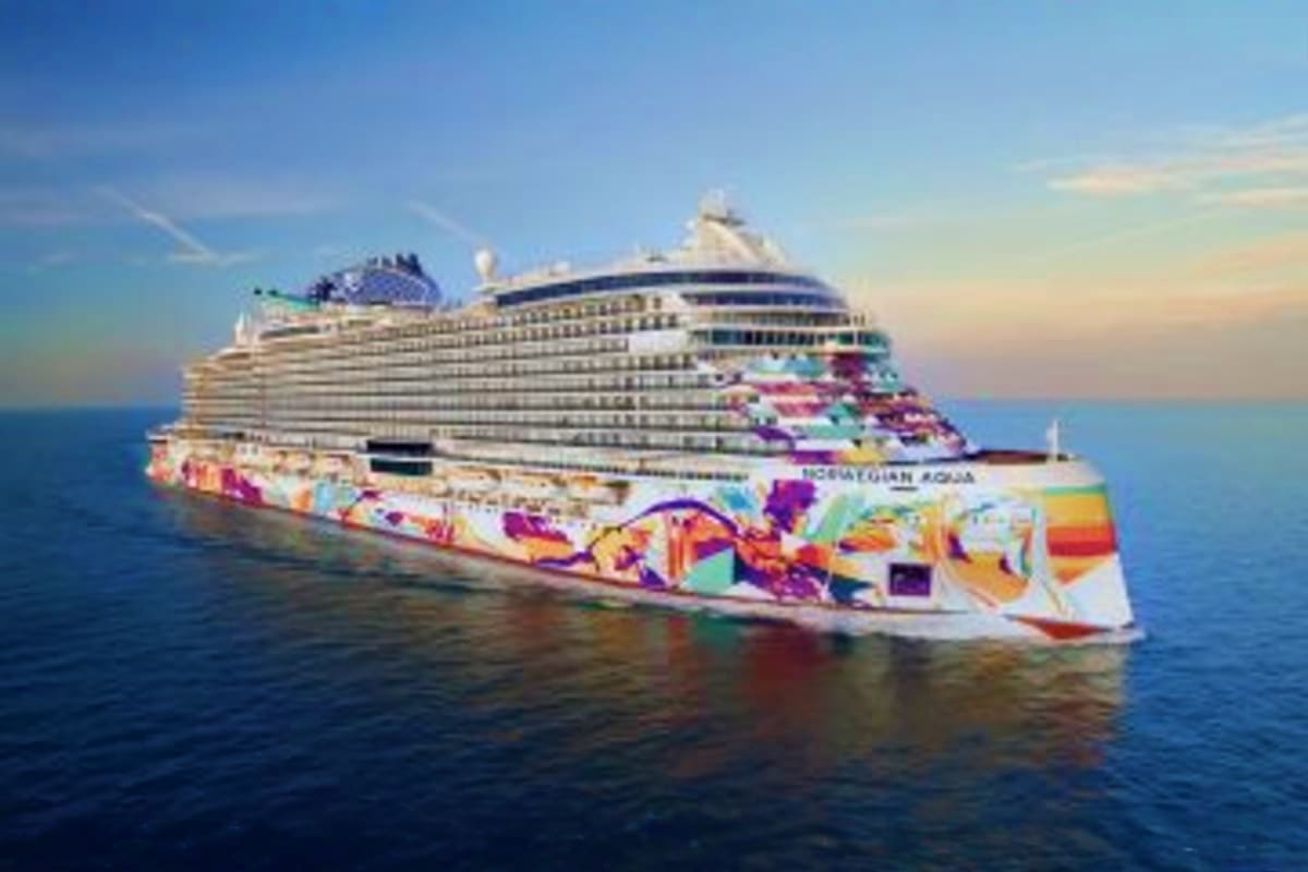 Norwegian Aqua cruise ship with colorful artwork on hull sailing on blue ocean water under clear sky