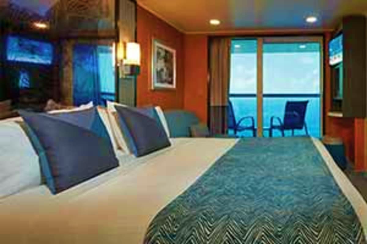 Norwegian Jade Japan Cruise Modern cruise ship cabin with queen bed, orange walls, ocean view balcony, and contemporary furnishings overlooking the sea