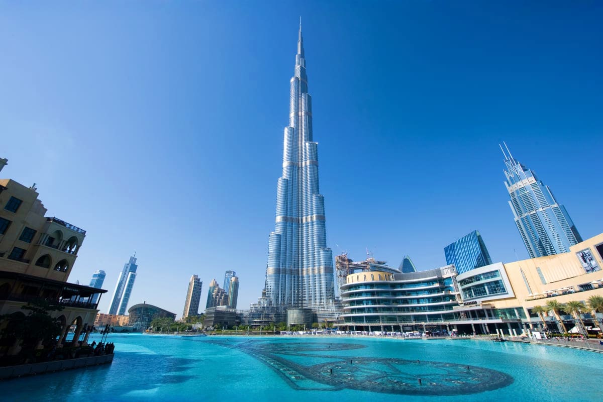 Burj Khalifa and Dubai skyline with turquoise fountain lake and modern buildings under clear blue sky