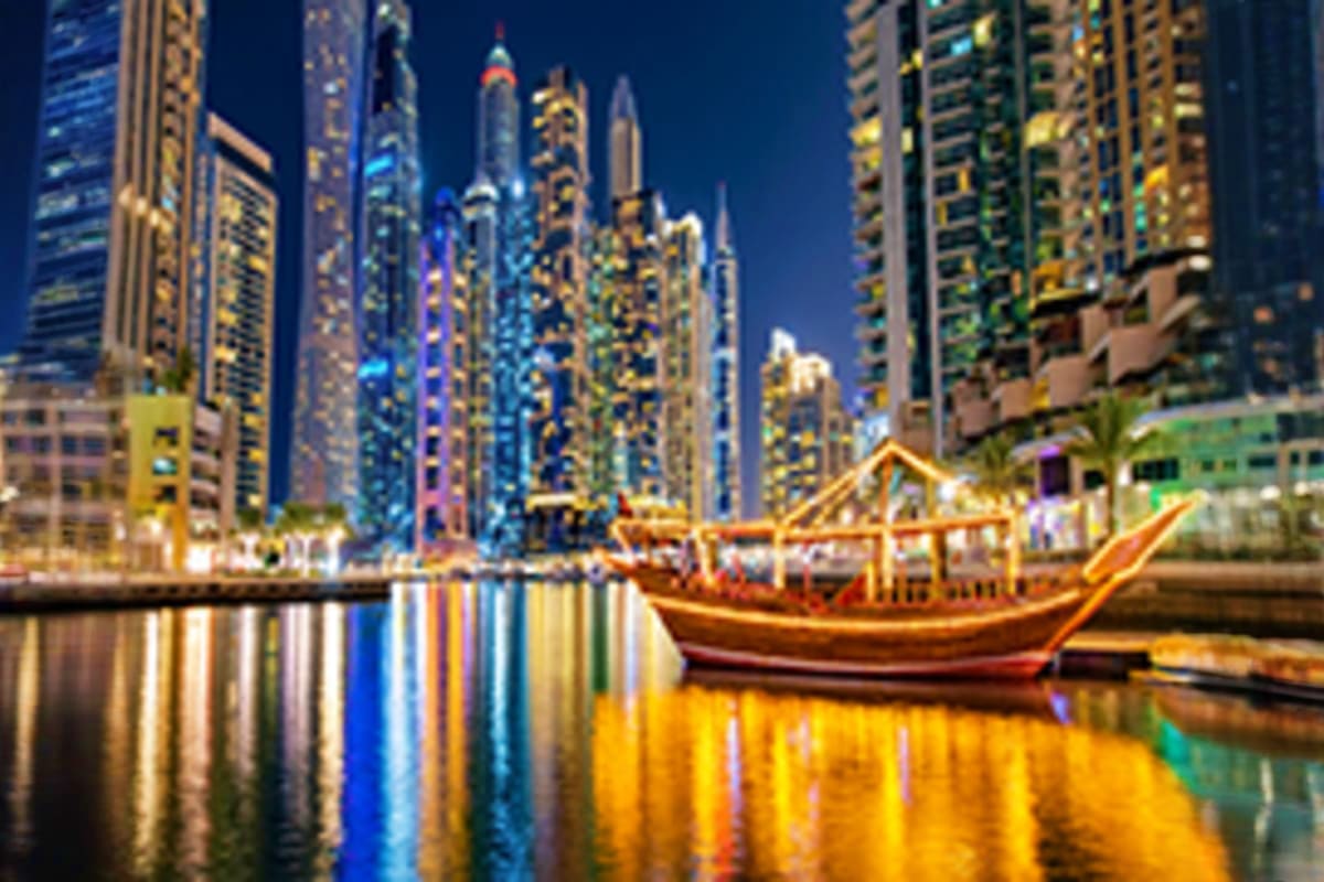 Traditional wooden abra boat on Dubai Creek at night with illuminated skyscrapers reflected in calm water