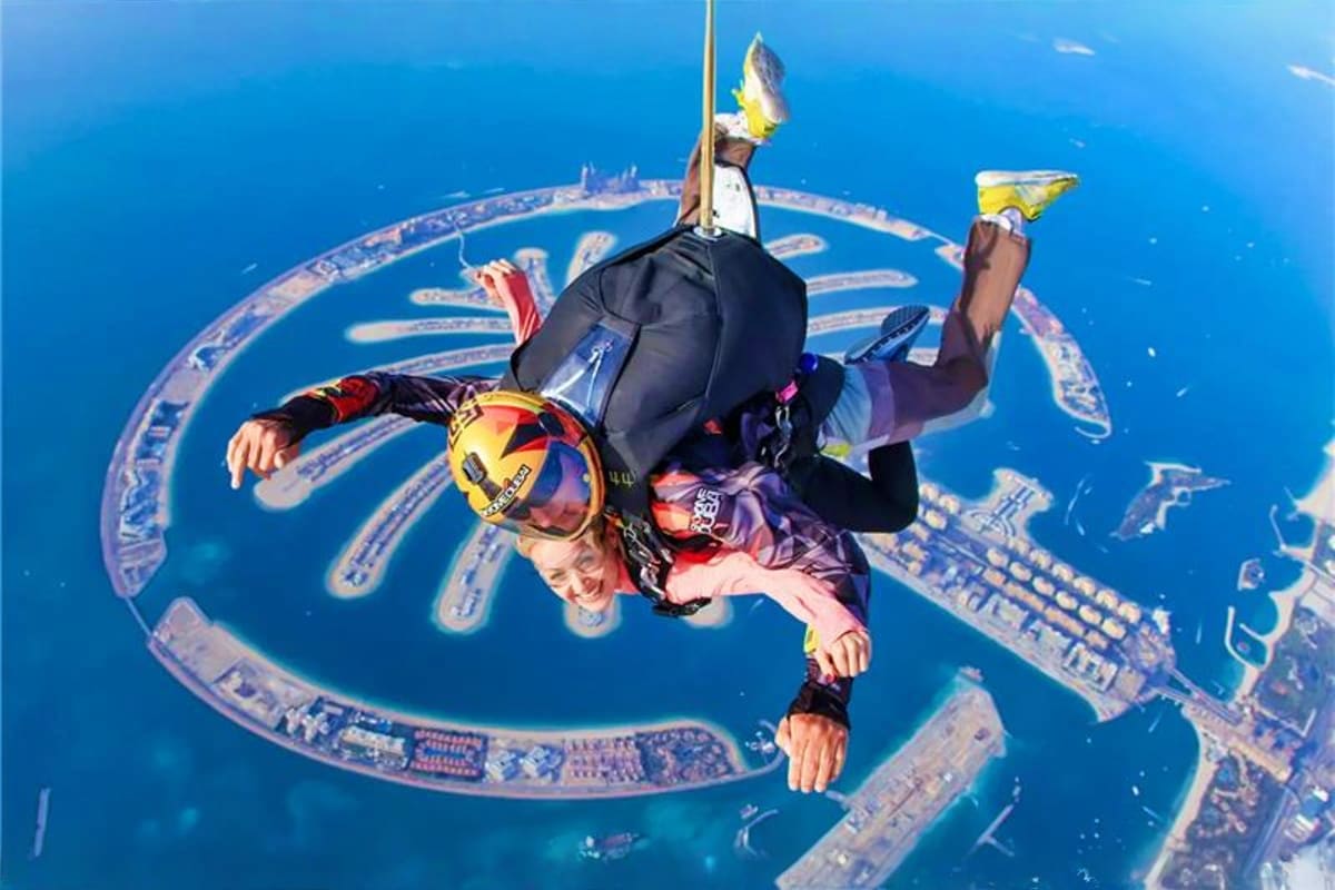 Skydiver in freefall above Palm Jumeirah island in Dubai with blue ocean and artificial palm-shaped development visible below