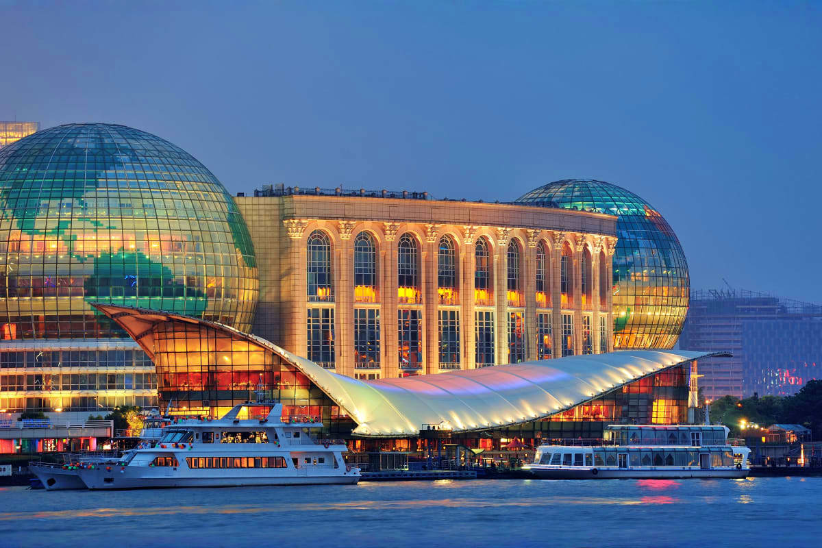 Lincoln Center for the Performing Arts illuminated at twilight with two domed glass structures, classical building, and tour 