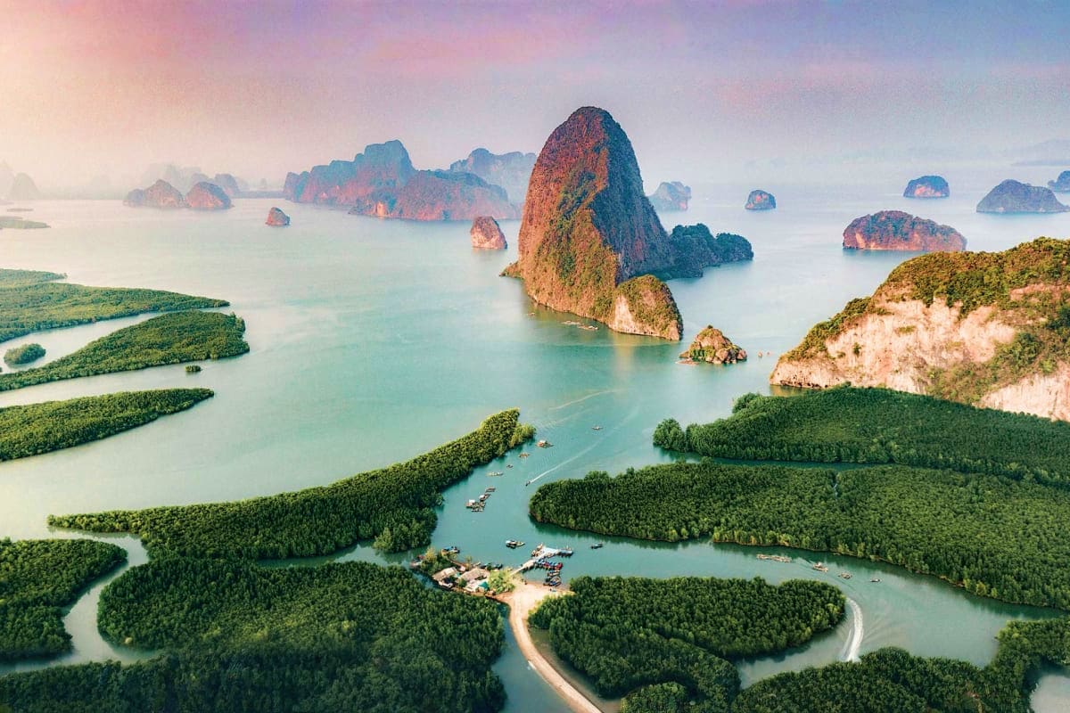 Aerial view of Phang Nga Bay with limestone karst formations, turquoise waters, mangrove forests, and traditional longtail bo