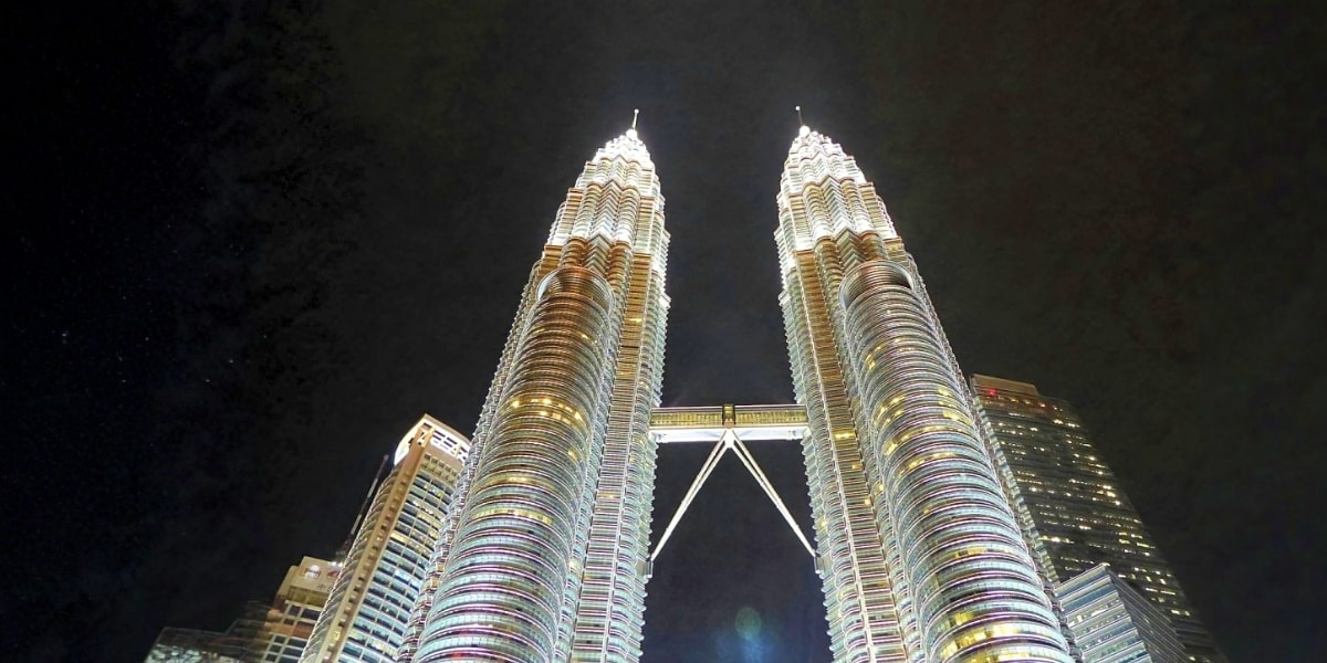Petronas Twin Towers illuminated at night in Kuala Lumpur, Malaysia, featuring distinctive Art Deco architecture and connecte