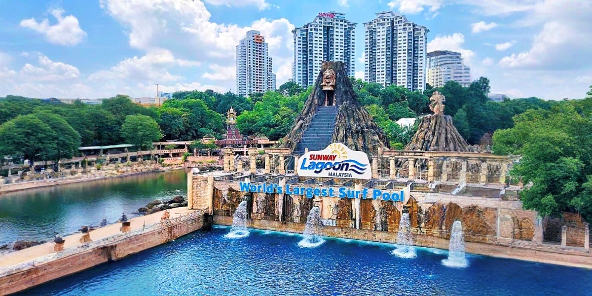 Sunway Lagoon Malaysia water park featuring giant carved mountain structures with cave entrances overlooking blue lagoon pool
