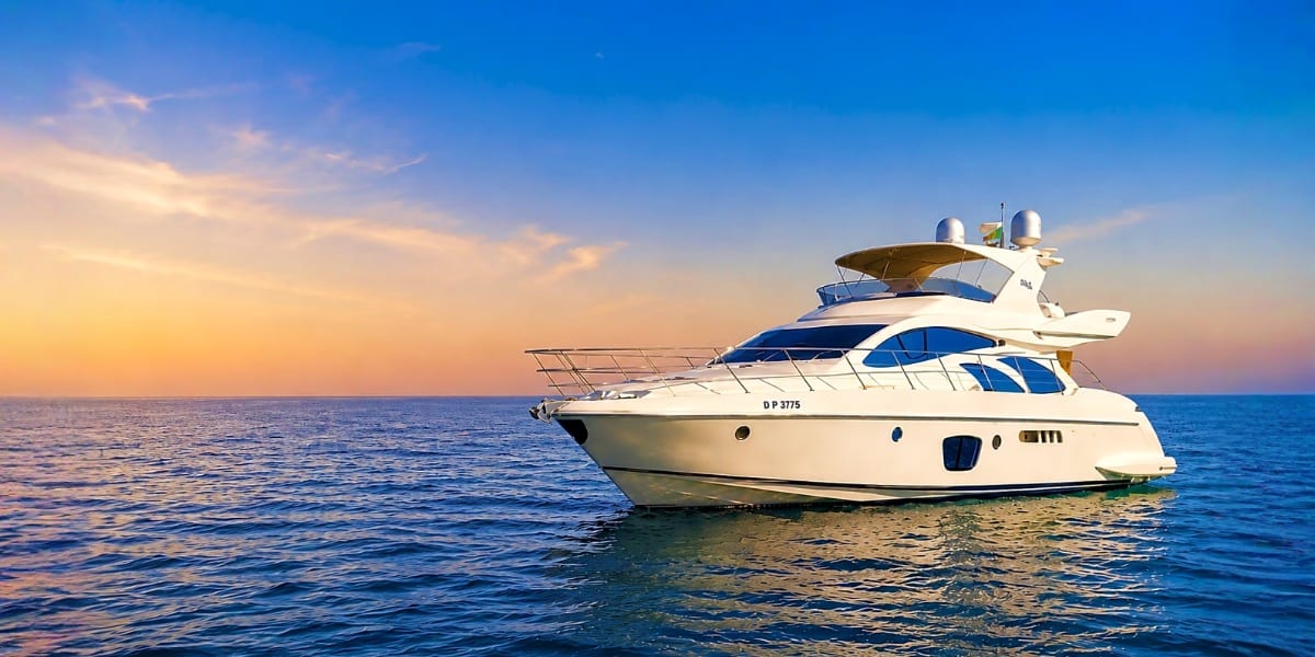 Luxury white and blue motor yacht anchored in calm blue water at sunset with clear sky