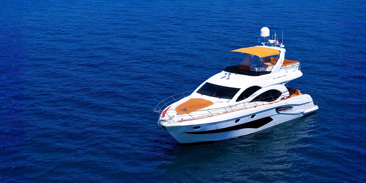 Luxury motor yacht anchored in deep blue Mediterranean water with white hull and tan canopy awning