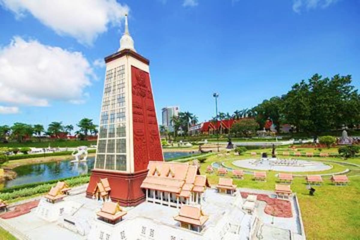 Miniature red and white pagoda tower at Mini Siam Pattaya theme park with landscaped gardens and pond in background