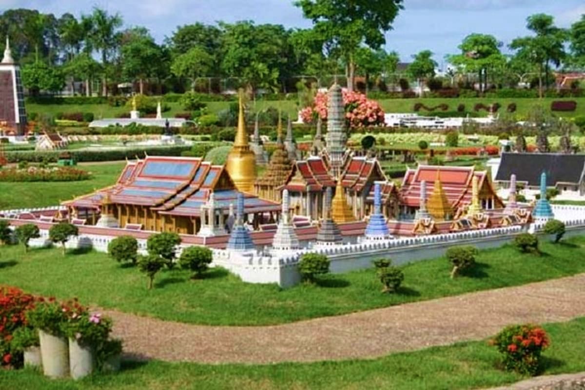 Miniature Thai Buddhist temple complex with golden spires and red-tiled roofs surrounded by landscaped gardens at Mini Siam P
