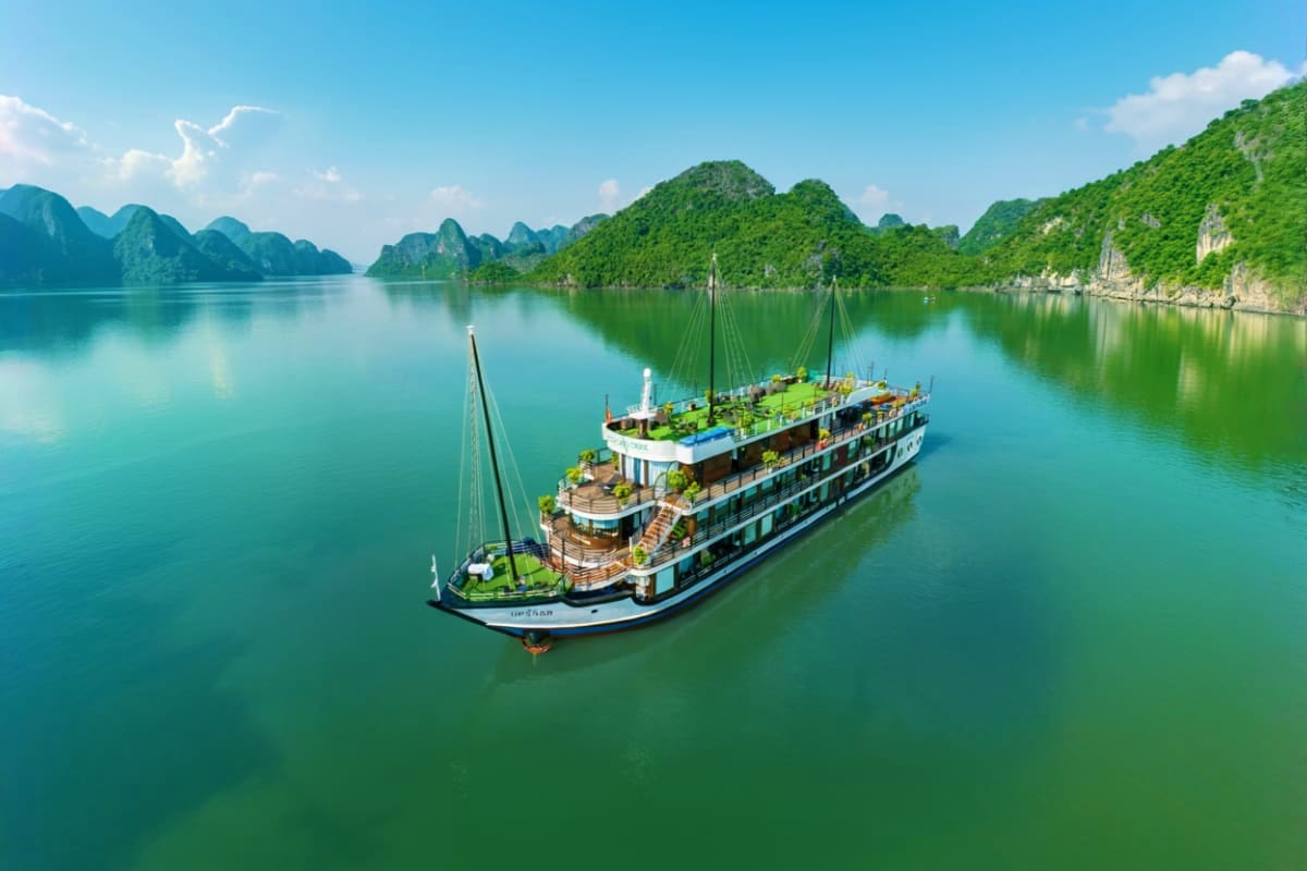 Luxury cruise ship anchored in emerald waters surrounded by limestone karst mountains in Ha Long Bay, Vietnam