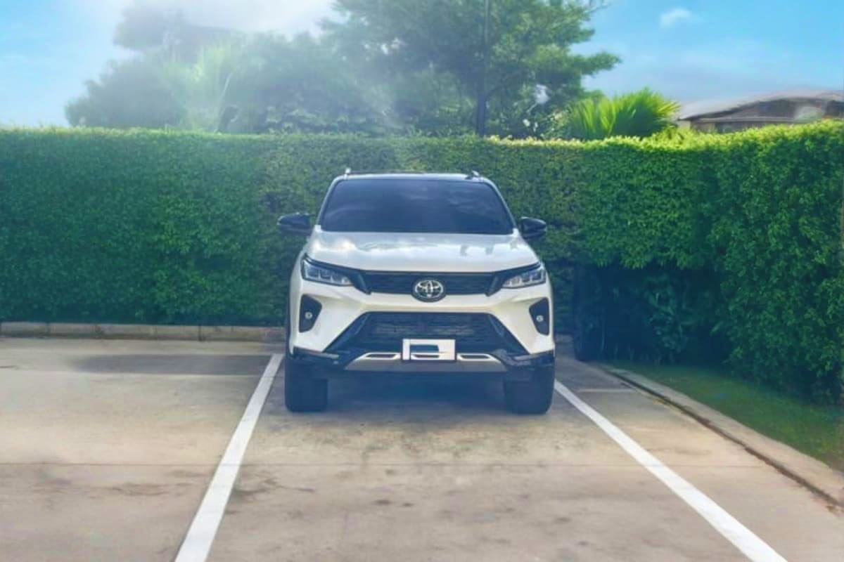 White Toyota SUV parked on driveway with green hedges, representing airport transfer service