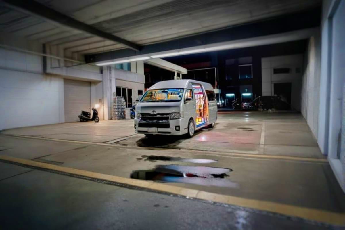 White Toyota van parked in covered airport terminal at night, ready for passenger dropoff service
